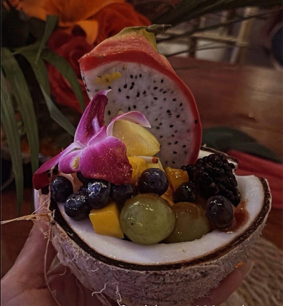 Fresh fruit and dragon fruit served in a coconut shell with an orchid