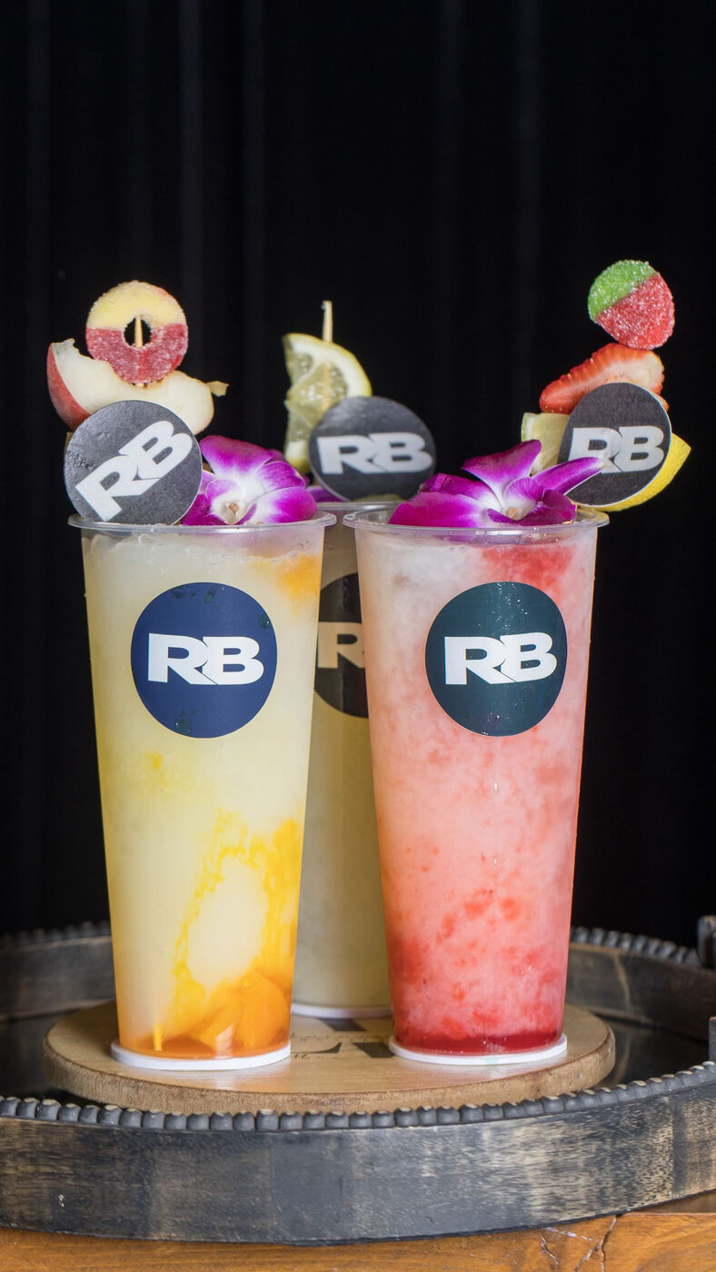 Three agua frescas garnished with fruit, candy, and custom logo toppers