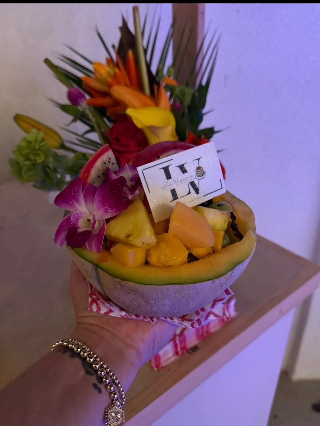 Melon bowl filled with tropical fruit and crowned with fresh flowers